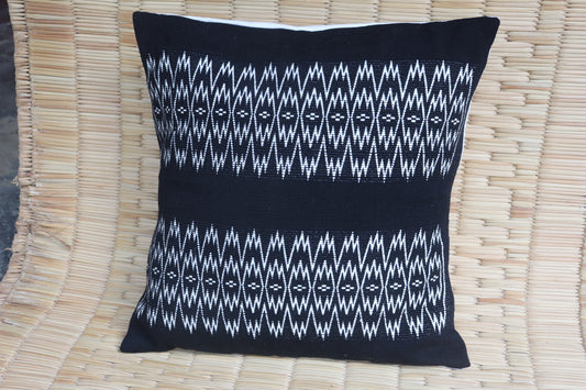 Black pillow with white geometric pattern on a woven mat
